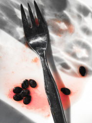 an eaten up watermelon with a fork and with juice and seeds of the melon on a white plate