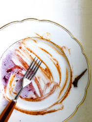 a fork is laying on an eaten up meal which looks like a painting on a gold rim plate