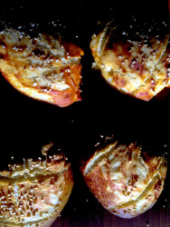 four freshly baked lye rolls with sesam on a dark wooden table