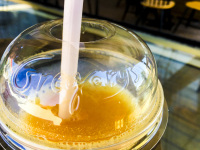 a yellow juice in a plastic cup with a drinking straw made by sugar