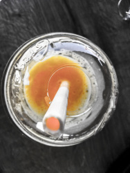 a white drinking straw made by sugar is staying in a yellow juice