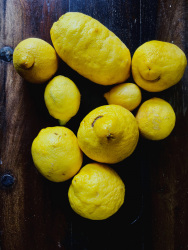 fresh yello lemons are laying on a dark wooden table and some of them are looking like a laughing face