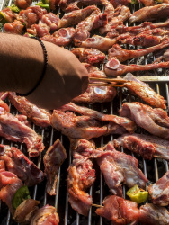 a lot of meat is laying on a grill and someone ist turning it