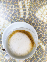 on an artful stony mosaik is standing a cup with yummi cappuccino