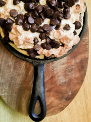 a sweet pizza with chocolate and flakes in a black wrought iron pan