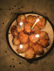 birthday candles on sweet fritters with cinammon on a plate