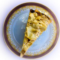 a peace of cake with meringue on a red and gold rim plate