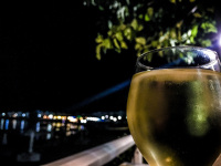a glass cold white wine with lights of a village in the night in the background