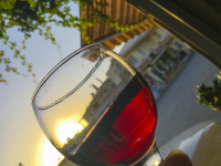 a glass of red wine by sunset in the street of a greek village