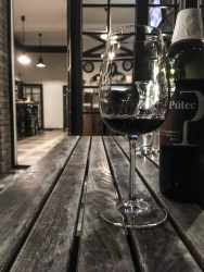 a glass and a bottle of slovak red wine on a wooden table in a restaurant