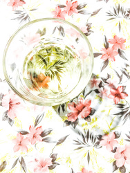 on a tablecloth with light pink flowers is standing a glass of white wine