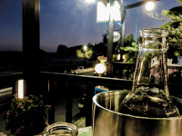 a bootleneck in a bottle cooler on a table of a restaurant by sunset