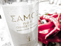 on a table you see red pepperoni and a bottle wine with a white lable where lettering samos