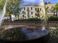 behind a glass of red wine there are houses in neoclassicist style