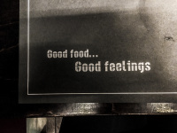 a black paper with lettering good food good feelings mat on a black table