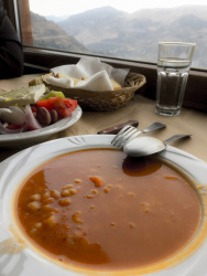 a plate of bean soup in front of a window in a mountain landscape