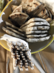 a yellow bowl filled with pita bread and with wooden forks