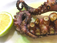 grilled ocotopus with a half lemon on a plate