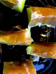 some in serrano ham wrapped peaces of honeydew melon on a black plate