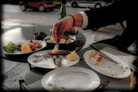 at a tasting greek food on half full and half empty plates someone takes some mustard