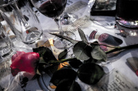 a pink rose and glasses of red wine are on a tablecloth wichh is painted with sausages