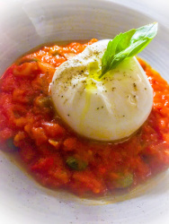 on top of a red tomatoe sauce is laying a buffallo mozarella with some basil