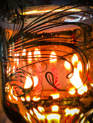 a glass filled with champagne with candles in the background