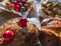 colorful easter eggs, a greek easter bread with sesame, a raisin braid and greek koulouria on an easter breakfast table