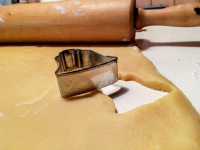 a rolling pin and a cookie shape in form of a bell on a cookie dough