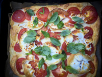 a pizza with tomatoes, goat cheese and basil rigth out of the oven