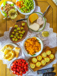 a tv-picknick with treats like strawberries, grapes, apricots, potatoe chips, cheese and grape skewers, little pizza, pie and various cheese