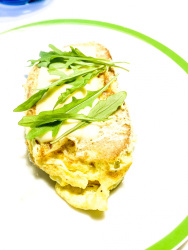 a slice of bread with egg and cheese and arugula on the top for a little picknick