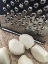 cloves of garlic are rubbed by the right grater for a tzatziki