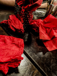 after an eaten up meal there are red crunched up serviettes on a dark brown wooden table