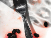 an eaten up watermelon with a fork and with juice and seeds of the melon on a white plate