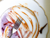 a fork is laying on an eaten up meal which looks like a painting on a gold rim plate