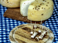 three wheels of cheese and wooden boards for tasting cheese are on a blue white checkered tablecloth