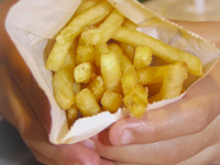 a child hand is holding a portion of hot french fries