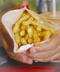 a child hand is holding a portion of hot french fries