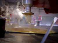 someone sprinkles sugar and cinnamon on a steaming crepe