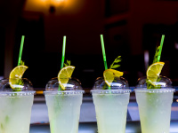 four cold softdrinks in plastic cups with drinking straws and lemon slices