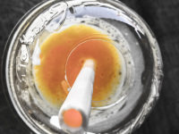 a white drinking straw made by sugar is staying in a yellow juice