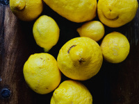fresh yello lemons are laying on a dark wooden table and some of them are looking like a laughing face