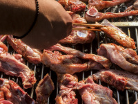 a lot of meat is laying on a grill and someone ist turning it