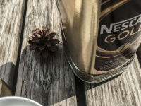 a pine cone, a big glass of nescafe and en empty white cup are waiting for a nice outdoor coffee time