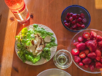 a little meal on a sunny table with tagliatelle, salad, tomatoes, strawberries and rose wine