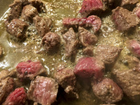 beef is frying in a pan with oil for preparaiting greek stifado