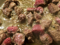 beef is frying in a pan with oil for preparaiting greek stifado
