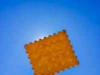 a light brown butter biscuit in front of the sun at a blue sky
