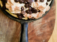a sweet pizza with chocolate and flakes in a black wrought iron pan